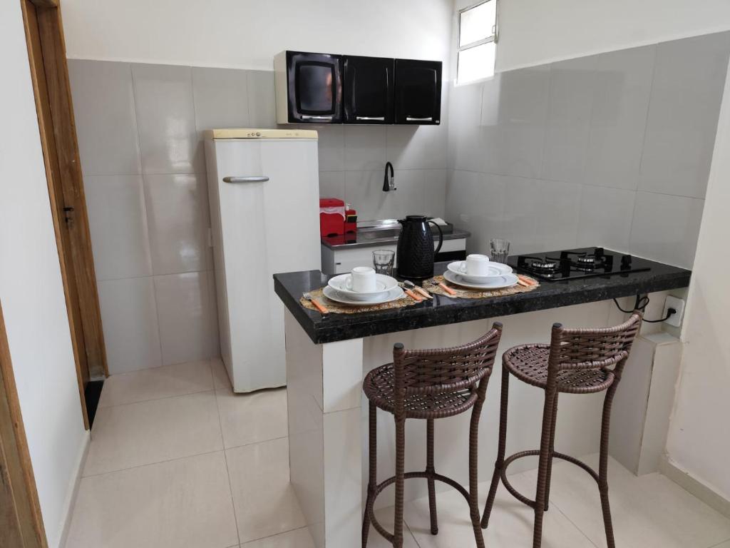 a kitchen with a counter with stools and a refrigerator at Apartamento central - Feijó 01 in Vitória da Conquista