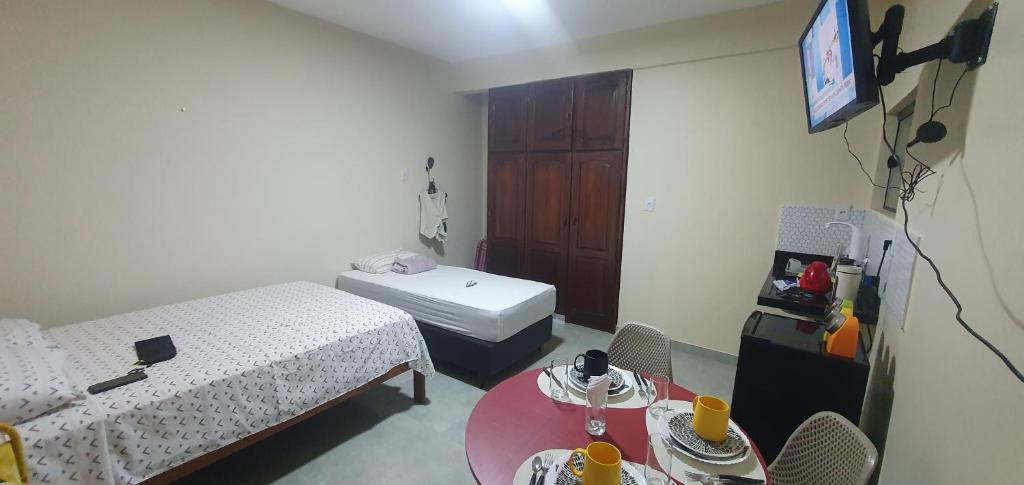 a room with two beds and a table and a tv at Studio Figueira, Sol in Santarém