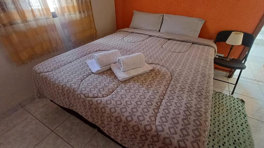 a bedroom with a bed with two towels on it at Casa amarela - Perto do Centro in Poços de Caldas