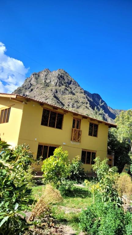 a large yellow house with a thatched roof at Lavanda lodge Ollantaytambo in Ollantaytambo