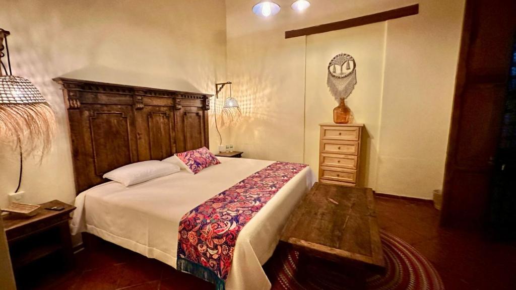 a bedroom with a bed with a wooden headboard and a table at Casona Bartolome in Morelia
