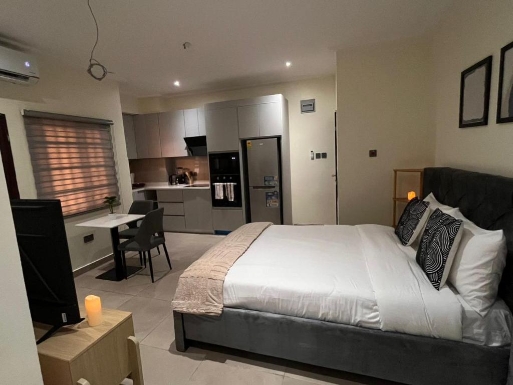 a bedroom with a large bed and a kitchen at The Veron, Dzorwulu in Lapaz