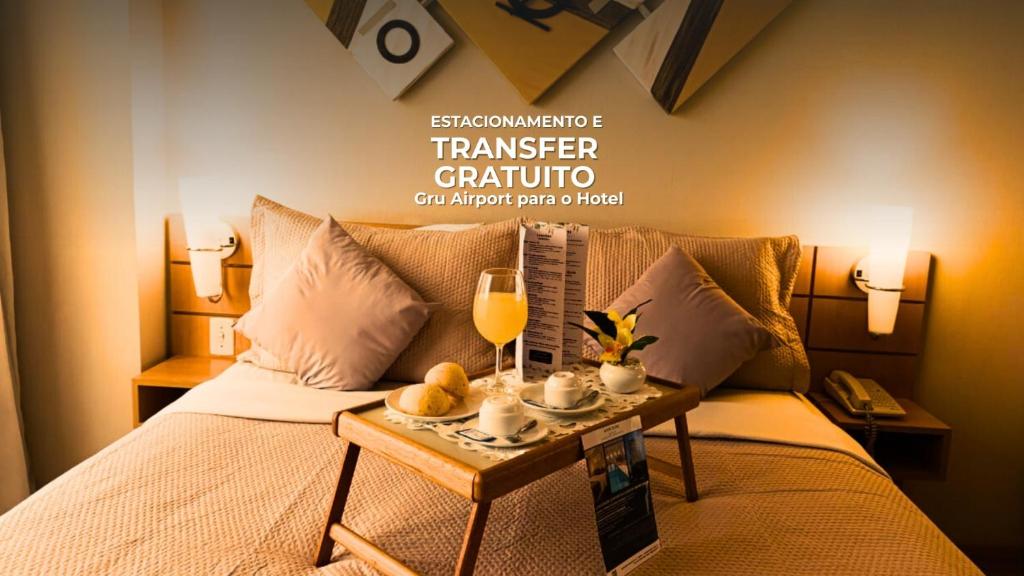 une chambre avec un lit, une table et une coupe de champagne dans l'établissement Hotel aeroporto Guarulhos, à Guarulhos