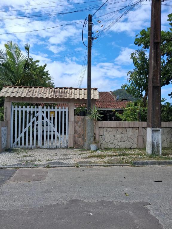 ein Haus mit einem weißen Tor und einem Zaun in der Unterkunft Kitinete Quarto para casal in Matinhos