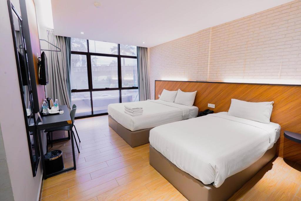 een hotelkamer met twee bedden en een raam bij Hotel 99 Seri Kembangan Serdang in Seri Kembangan