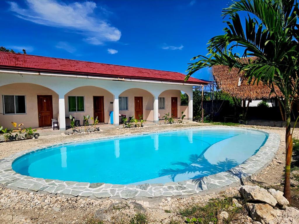 a villa with a swimming pool in front of a house at Mangoverde Guesthouse in Moalboal
