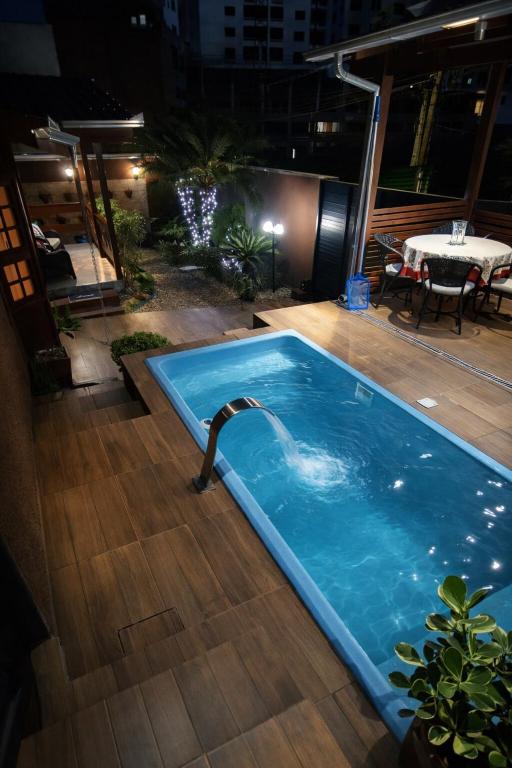 a swimming pool with a water fountain on a deck at Casa com Piscina e Jacuzzi, Próxima da Praia Brava in Itajaí
