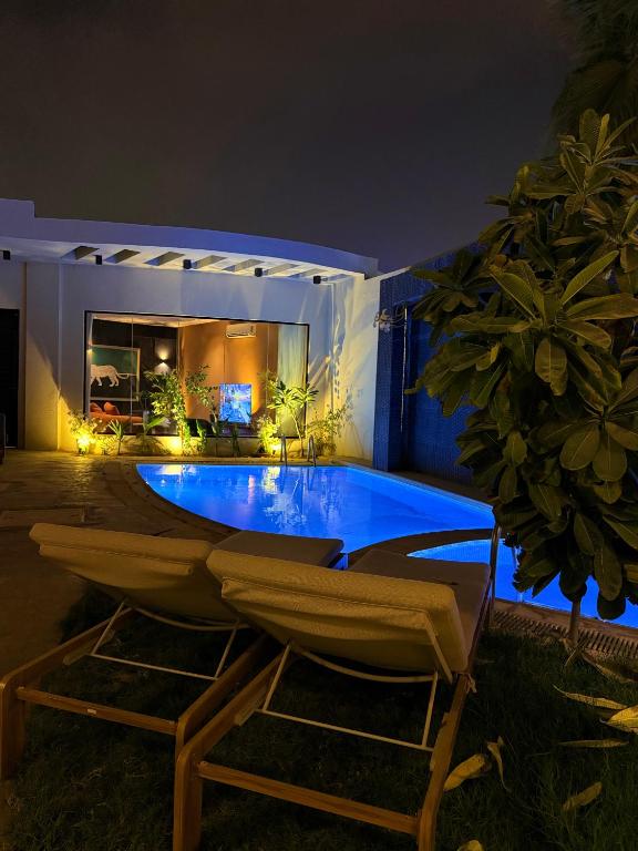 a swimming pool with two chairs in front of a house at Cali chalets in Riyadh