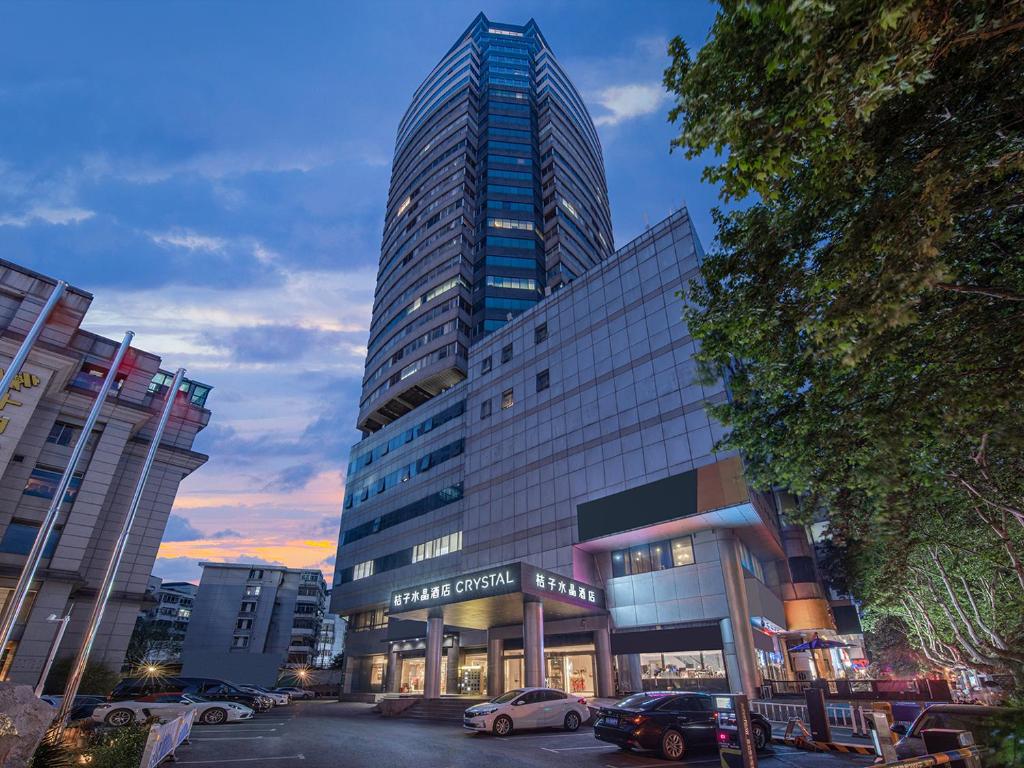 a tall building with cars parked in front of it at Orange Crystal Hotel Nanjing Drum Tower in Nanjing