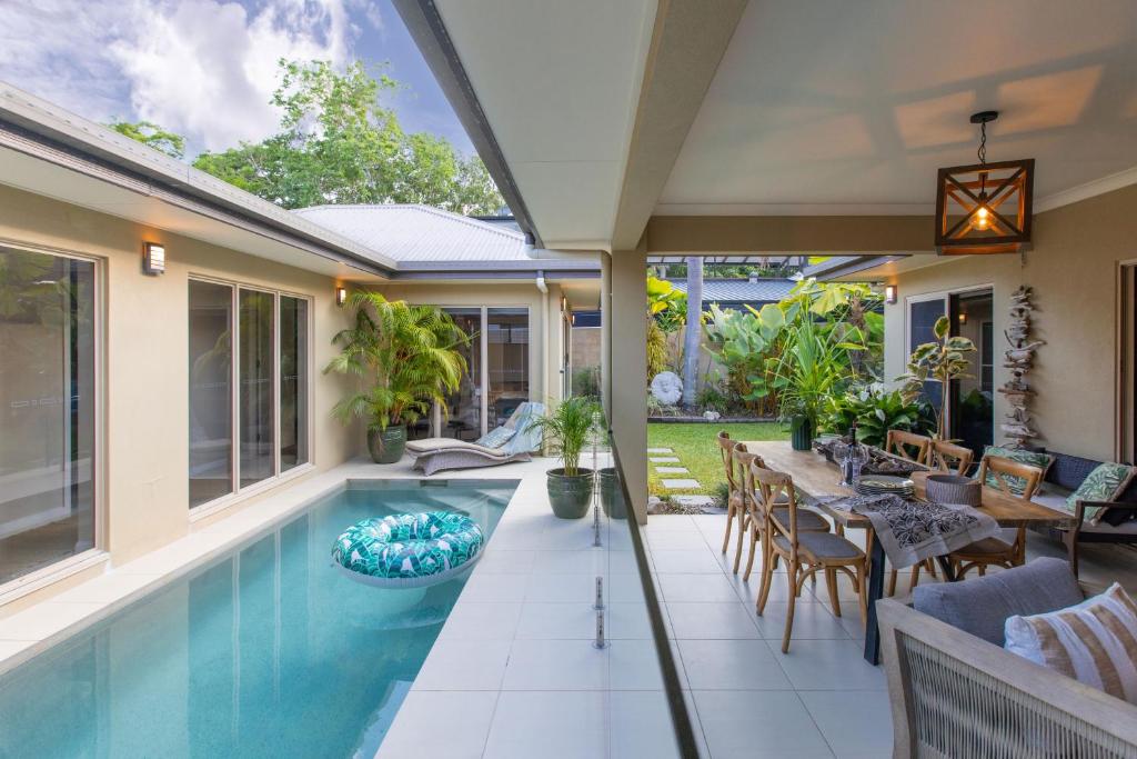 eine Außenterrasse mit Swimmingpool und Tisch und Stühlen in der Unterkunft Escapades @ Palm Cove in Palm Cove