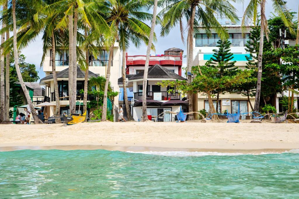 een strand met palmbomen voor een gebouw bij La Suerte Villa in Boracay