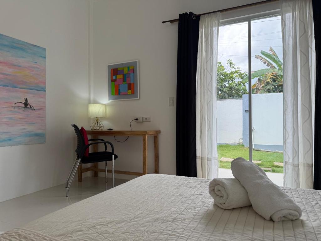 a bedroom with a bed and a desk and a window at Ivorys Guesthouse in Panglao