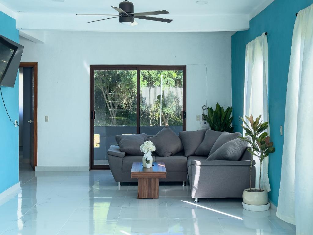een woonkamer met een bank en een plafondventilator bij Estancia Sofia in Puerto Escondido