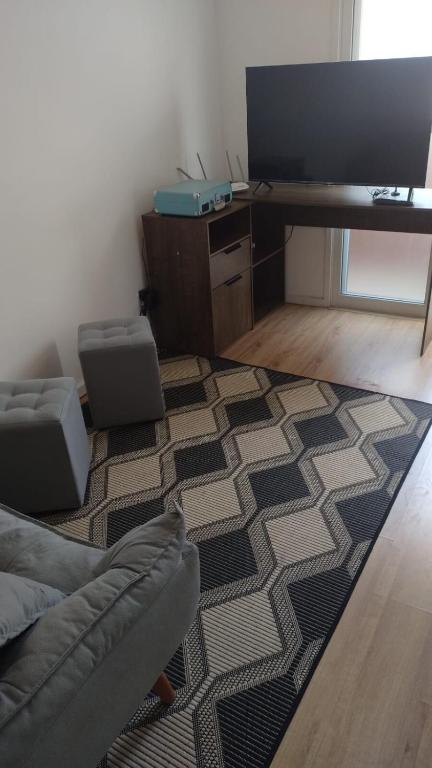 a living room with a couch and a desk with a television at APTO EASY Poços de Caldas in Poços de Caldas