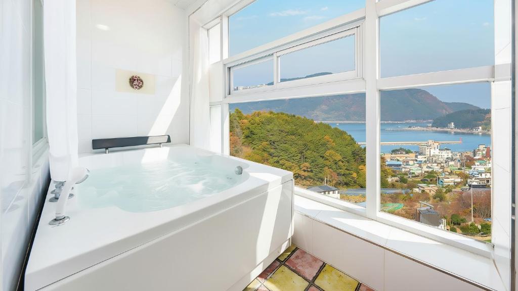 een witte badkamer met een groot raam en een bad bij Geoje Forest-Morning Spa Pension in Geoje 