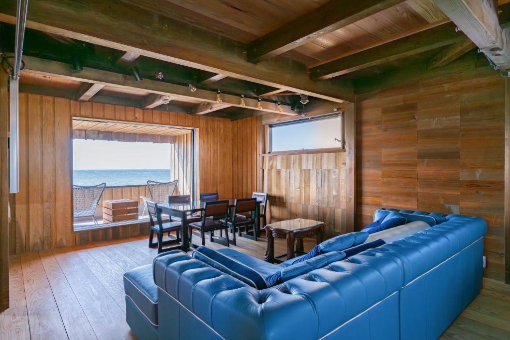 een woonkamer met een blauwe bank en een tafel en stoelen bij マーレゲストハウス in Fukui