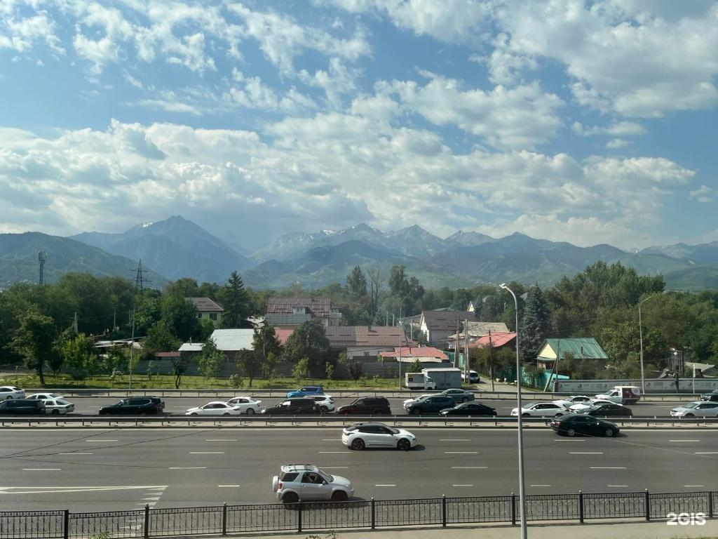ein Parkplatz mit Autos an einer Autobahn mit Bergen in der Unterkunft Mosh Mosh Boutique Hotel in Almaty