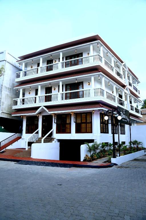 a large white building with balconies on a street at Le Zaina's Fort Hotel in Cochin