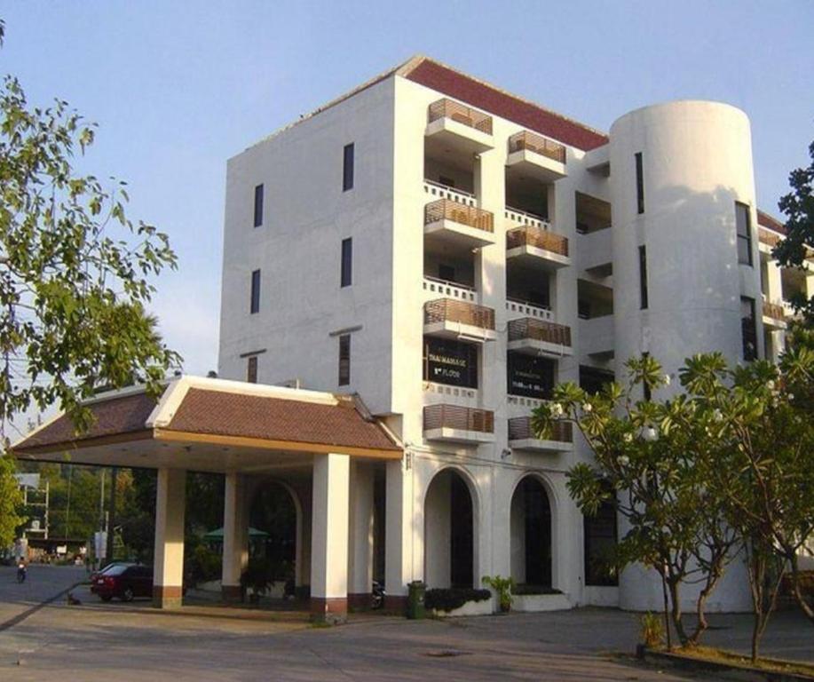 een wit gebouw met een parkeerplaats ervoor bij Royal Diamond Hotel in Phetchaburi