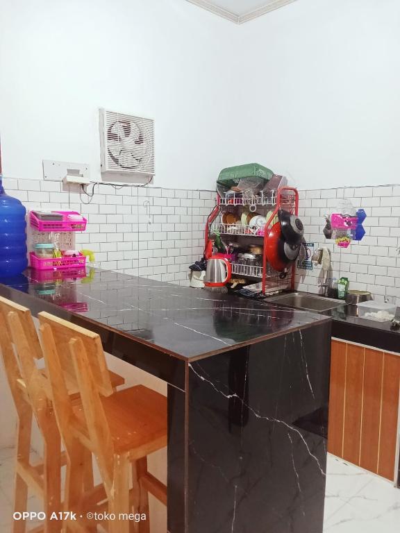 een keuken met een zwart aanrecht met 2 stoelen bij Uoemah gunung baturaden in Baturaden