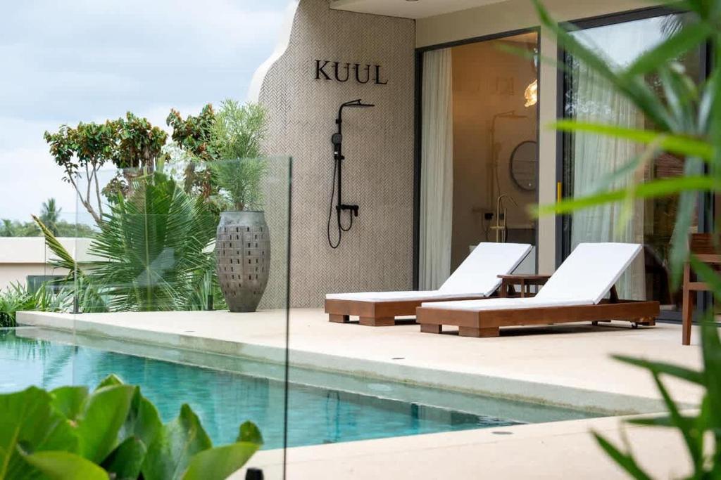 une piscine avec deux chaises longues à côté d'un bâtiment dans l'établissement Kuul villa 4 - Seaview & Stylish villa, à Baan Tai