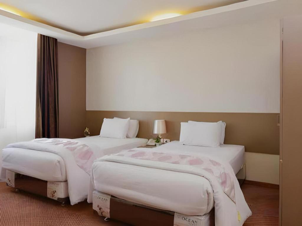 two beds in a hotel room with white sheets at Hotel Mekkah Banda Aceh in Lamglumpang