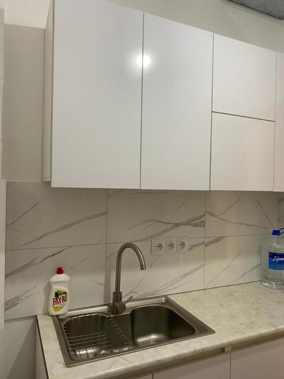 eine Küchentheke mit einer Spüle und weißen Schränken in der Unterkunft Коттедж in Bosteri