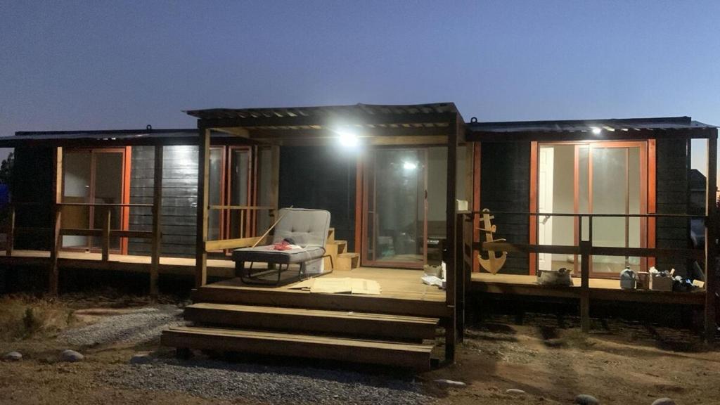 een huis met een veranda en een stoel op de trap bij Tiny Tunquen in Valparaíso