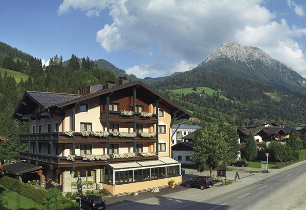 un grande edificio sul lato di una strada con una montagna di Hotel Alpina a Kleinarl