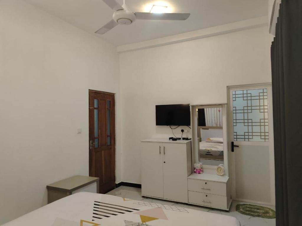 a white room with a bed and a tv at Stay Roside Villa Hikkaduwa in Hikkaduwa