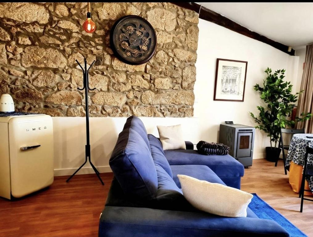 a living room with a blue couch and a stone wall at Casa Do Refugio Guest House in Covilhã