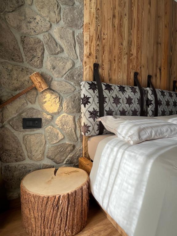 a room with two beds and a log stool next to a stone wall at Al Truciolo in Andalo