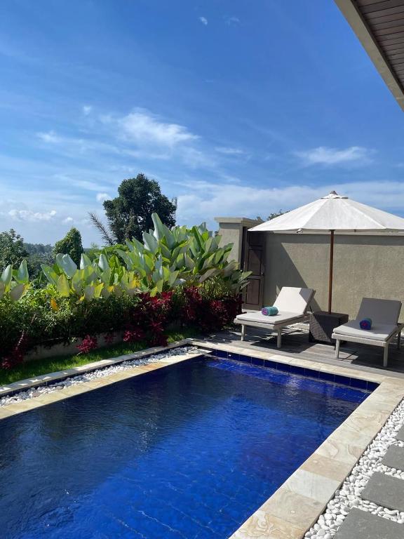 a swimming pool with an umbrella and a chair and an umbrella at SVARGA RENJANA ViLLA in Lombok