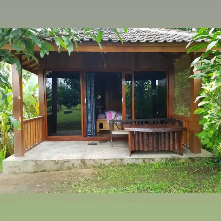 a wooden pavilion with a bench on a patio at waroeng bangket in Mantang