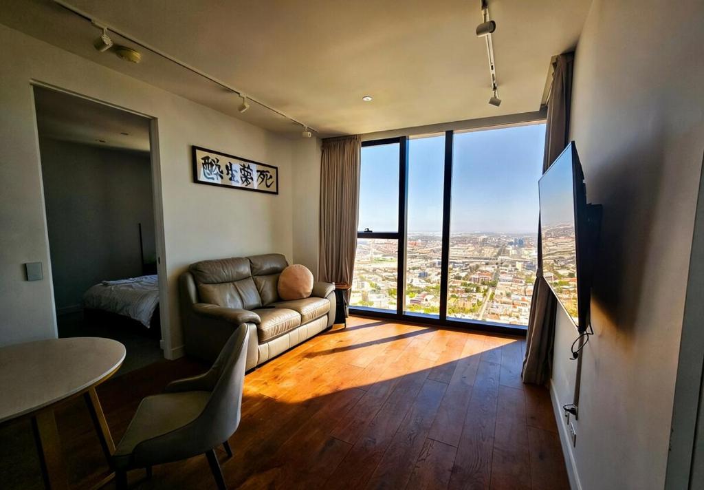 a living room with a couch and a large window at Sunset Sky Nest CBD 65F in Melbourne