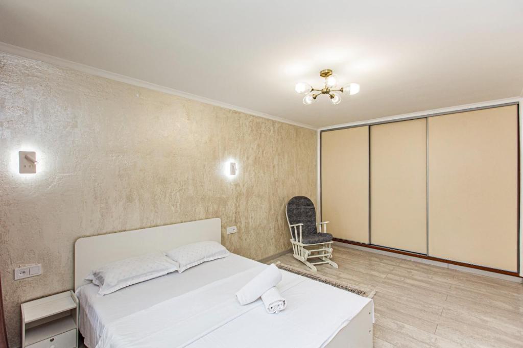 a bedroom with a white bed and a chair at Гоголя 117 in Almaty