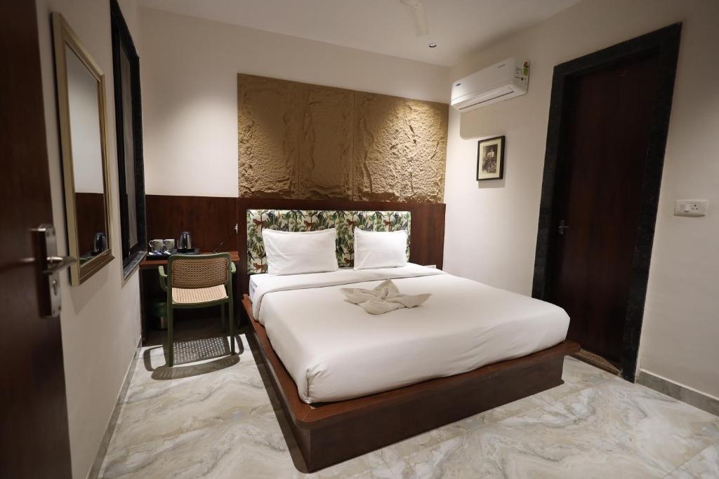 een slaapkamer met een bed met witte lakens en een tafel bij Hotel Destin in Gwalior