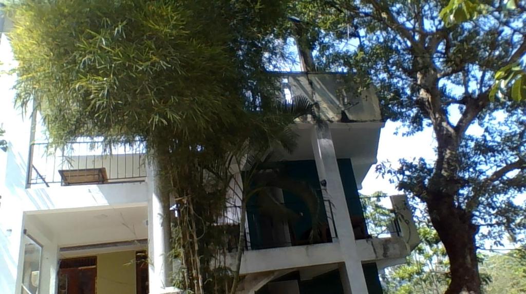 a white house with a tree in front of it at Green Wood Range in Kandy