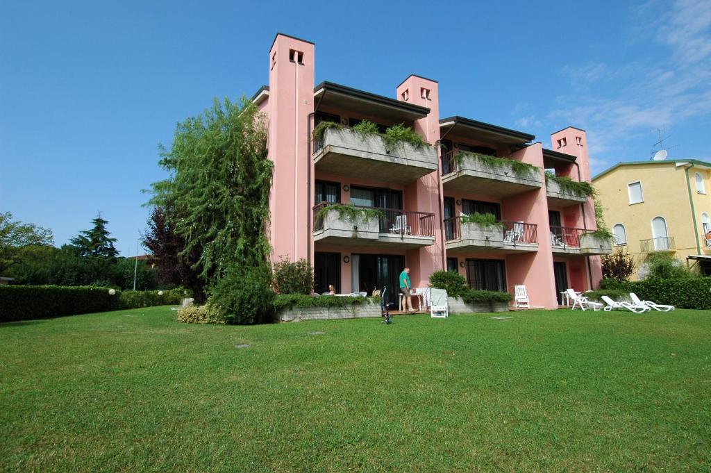 シルミオーネにあるResidence Virgilioのピンクのアパートメントで、前に広い芝生があります。