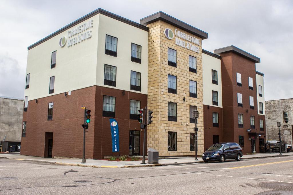 a building on the corner of a street with a traffic light at Cobblestone Hotel & Suites - Chippewa Falls in Chippewa Falls