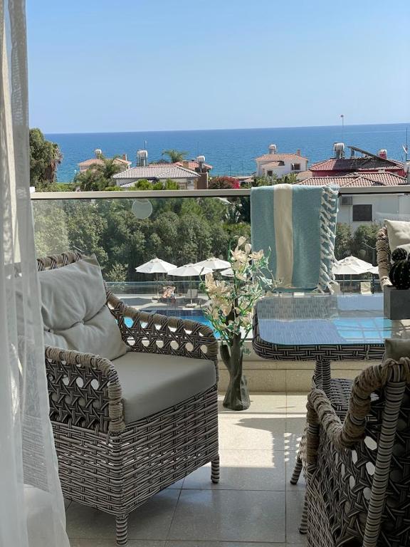 a balcony with wicker chairs and a table and a view of the ocean at Sea Breeze Suites by the Coast in Iskele