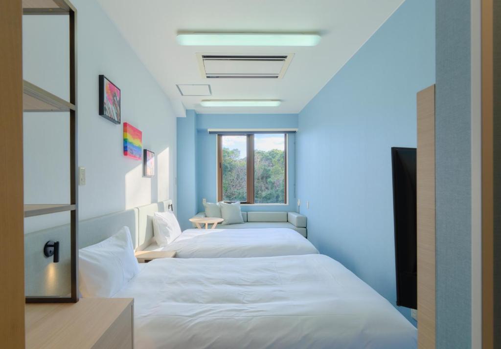 a row of beds in a room with blue walls at Red 28 in Ito