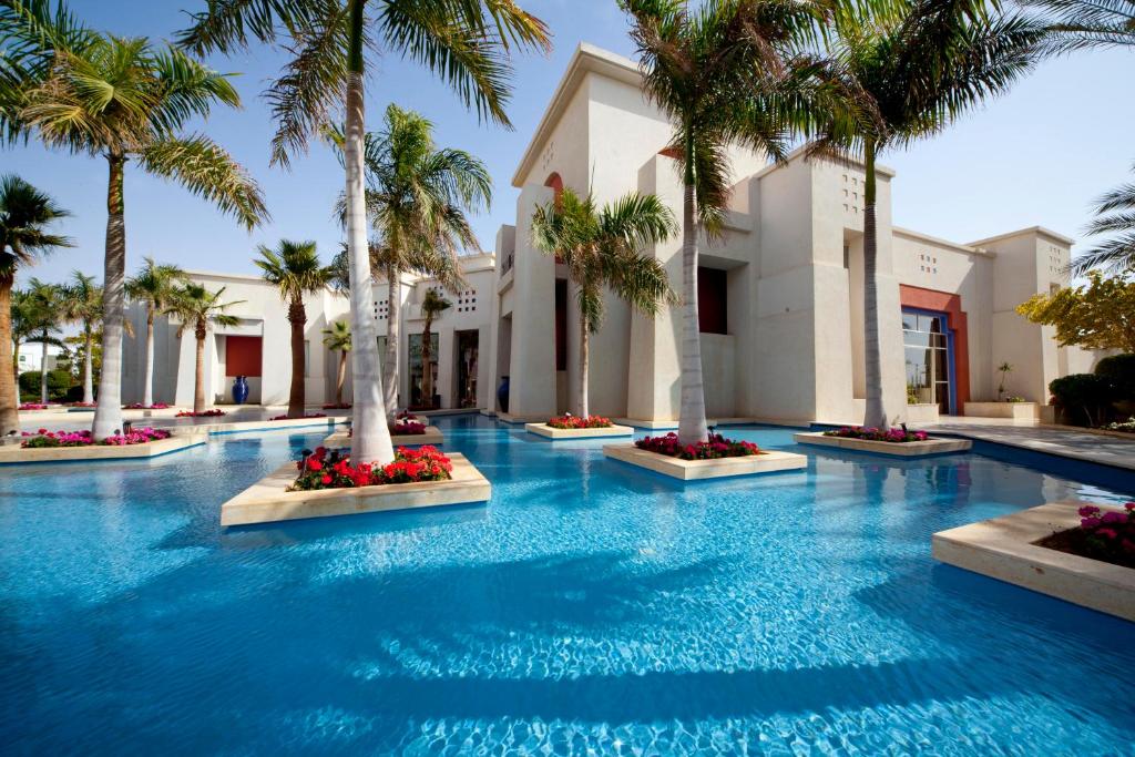 a swimming pool with palm trees in a resort at Grand Rotana Resort & Spa in Sharm El Sheikh