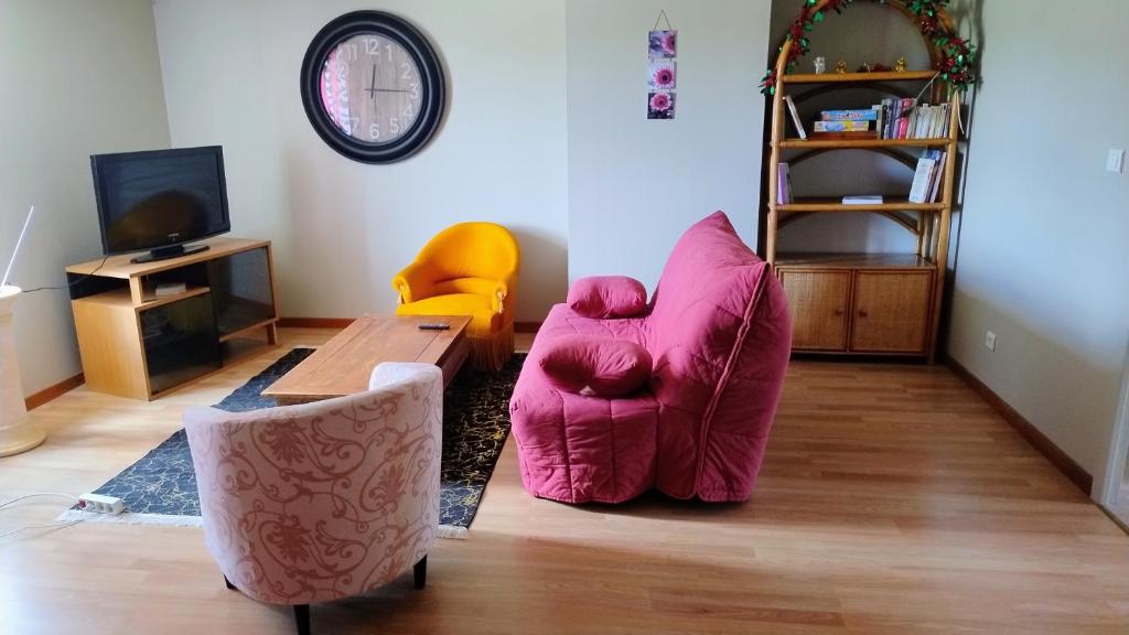 ein Wohnzimmer mit einem rosa Stuhl und einem Tisch in der Unterkunft La vie en rose in Courpière