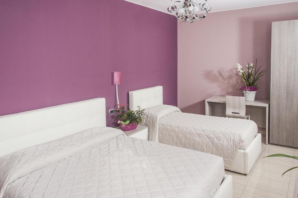 a bedroom with two beds and a purple wall at La Tarantola in Vermezzo
