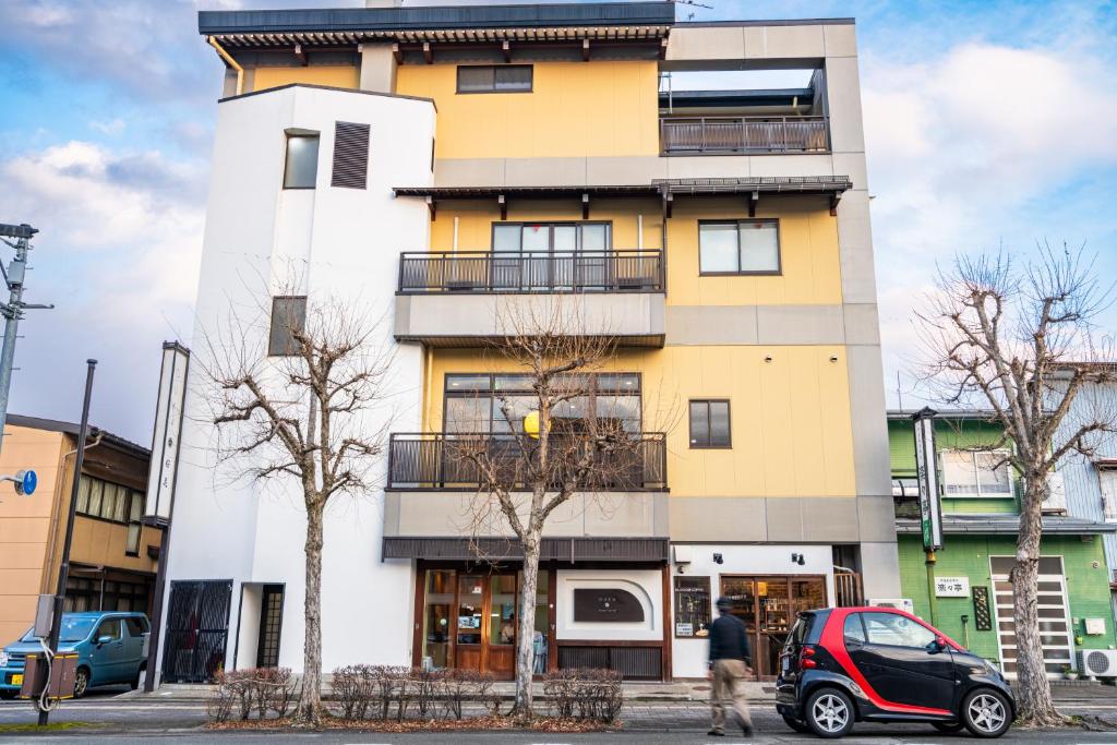 a yellow and white building with a car parked in front at Guest House Ouka in Takayama