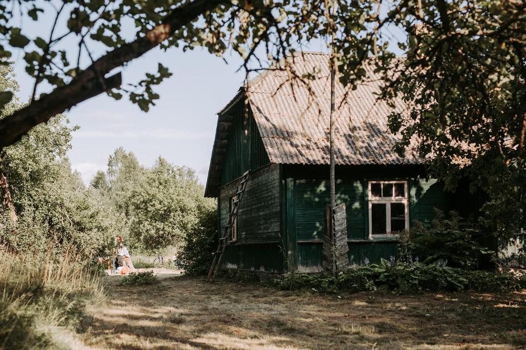 een oude groene kas met een vrouw die ervoor staat bij Retreat House in Lauvas