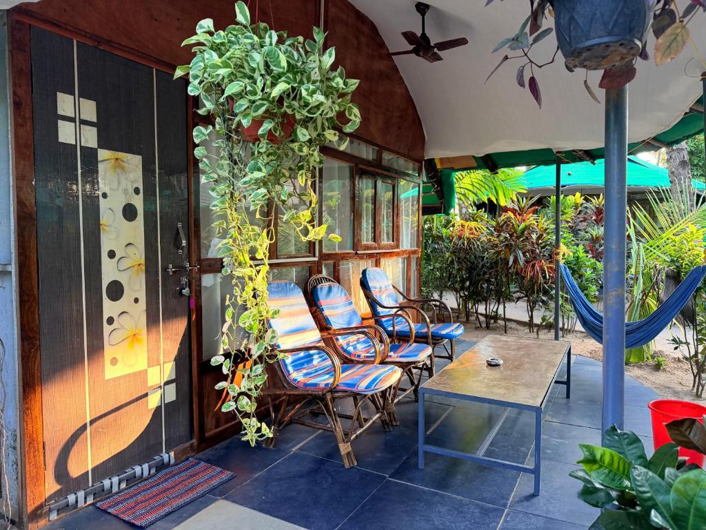 een terras met stoelen, een tafel en een parasol bij Lacto Cressida in Palolem