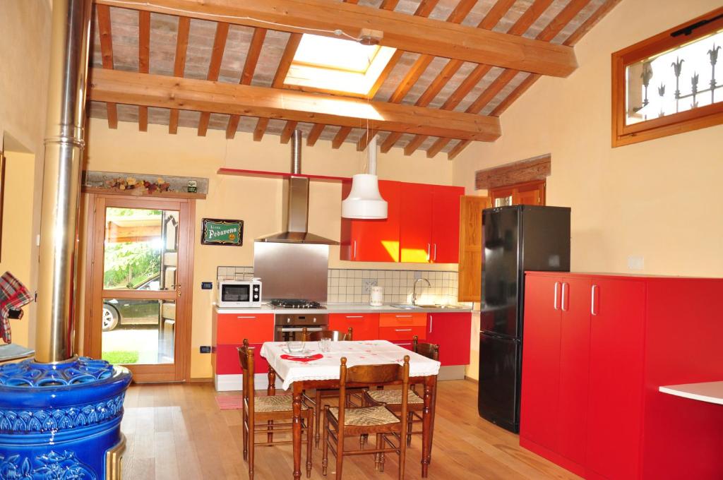 PortomaggioreにあるLa Casina sul Sandaloのキッチン(赤いキャビネット、テーブル、椅子付)