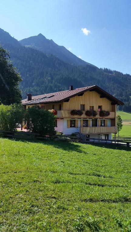 a building with a grass field in front of it at Haus Bilgeri in Nesselwängle